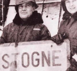 Soldados estadounidenses posando con el cartel del pueblo de Bastogne